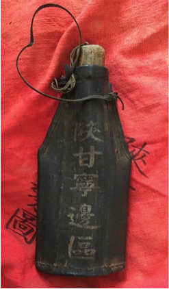 A Shaan-Gan-Ning Border Region-labeled water bottle, lying on a textile with the same text